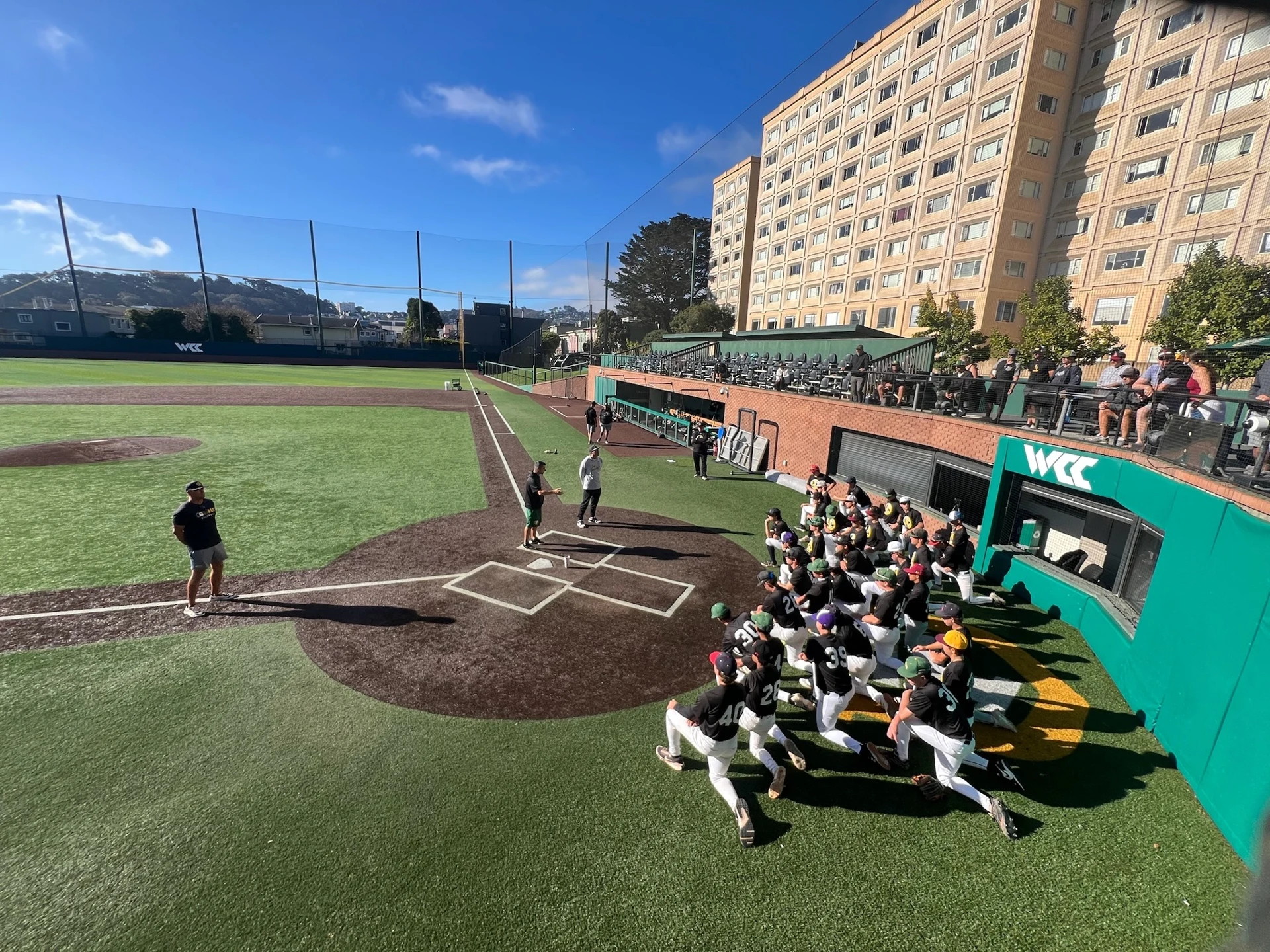 Diamond Access players listening to coaches beside home plate at a college baseball stadium